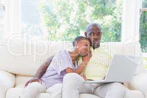 Happy smiling couple using laptop on couch