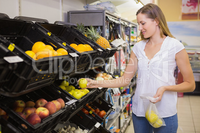 Smiling pretty blonde woman buying apples