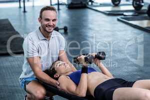 A muscular woman about to lift dumbbells