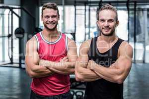 Two smiling muscular men with arms crossed