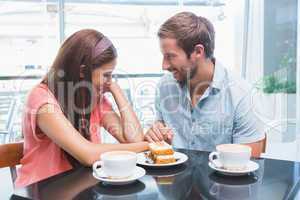 Young happy couple looking at each other while eating cake