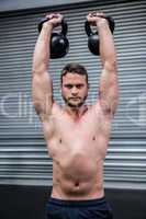 Portrait of muscular man lifting two kettlebells