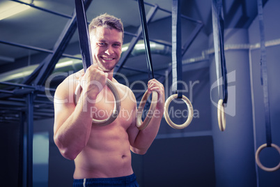 Portrait of smiling muscular man doing ring gymnastics