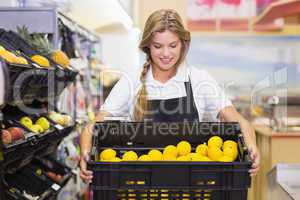 Smiling staff woman holding a box with fresh vegetables