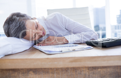 Tired businesswoman sleeping at her desk