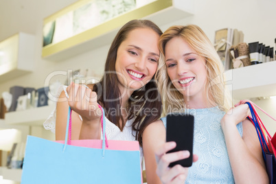 Happy women friends looking at smartphone