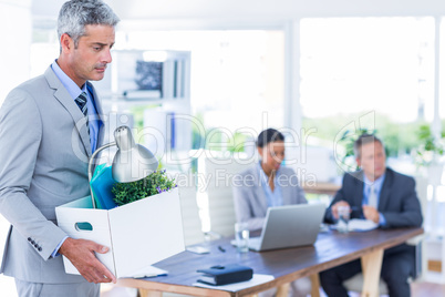 Businessman holding box with his colleagues behind him