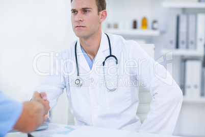 Serious doctor shaking hands