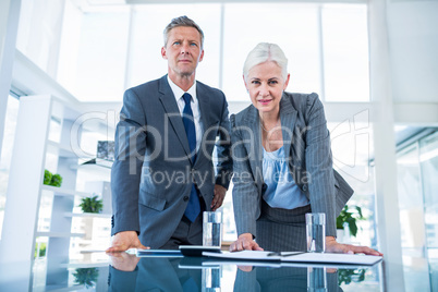 Business people looking at camera behind desk