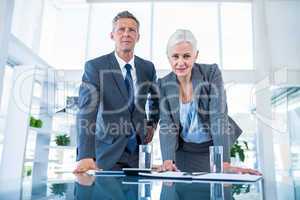 Business people looking at camera behind desk