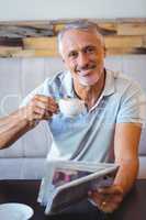 Smiling man having cup of coffee reading newspaper