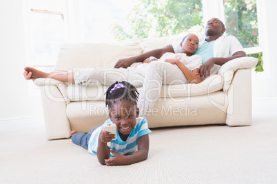 Pretty couple sitting on couch and their daughter playing