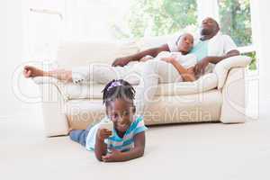 Pretty couple sitting on couch and their daughter playing