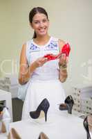 Young smiling woman looking at the camera with a shoe in her han