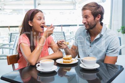 Young happy couple eating cake together