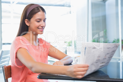 Young happy woman reading the newspaper