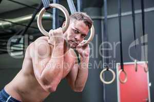 Portrait of muscular man doing ring gymnastics