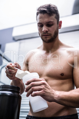 Muscular man making protein cocktail