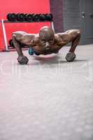 Portrait of muscular man doing push-ups with dumbbells