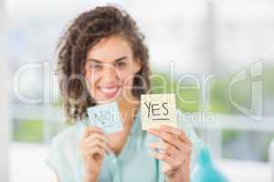 Smiling businesswoman holding yes and no sticks