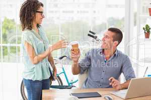 Businesswoman handing a mug of coffee to his colleague