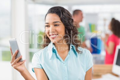 Young designer texting  with her colleagues behind her