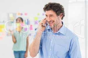 Businessman having phone call while his colleague posing