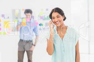 Businesswoman having phone call while her colleague posing