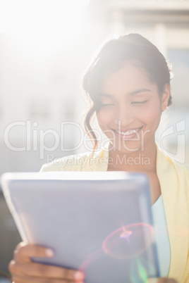 Casual businesswoman smiling at camera holding tablet pc