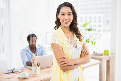 Smiling woman posing in front of her colleague with arms crossed