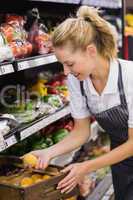 Smiling blonde worker taking a vegetables