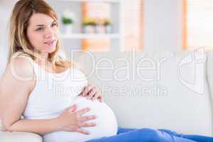 Pregnant woman touching her belly on the couch