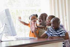 Happy smiling family chatting with computer together