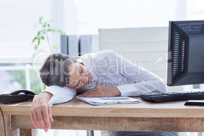 Tired businesswoman sleeping at her desk