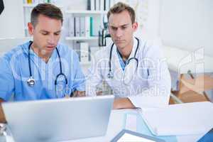 Concentrated medical colleagues working with laptop