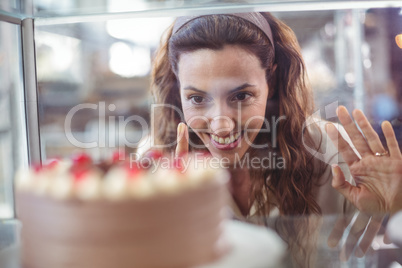 Pretty brunette looking at chocolate cake through the glass