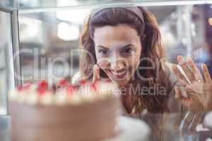 Pretty brunette looking at chocolate cake through the glass