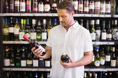 A handsome looking at wine bottle