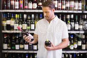 A handsome looking at wine bottle