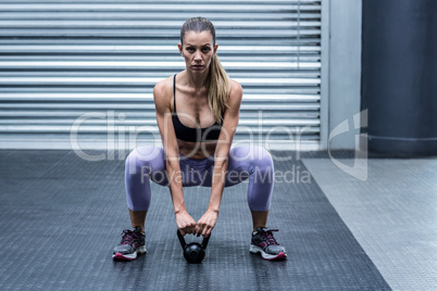 A muscular woman lifting kettlebells