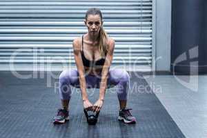 A muscular woman lifting kettlebells