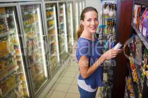 Happy pretty woman taking a product on shelf