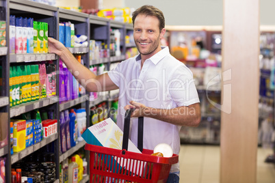 Portrait of a smiling handsome taking a product in shelf