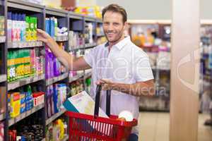 Portrait of a smiling handsome taking a product in shelf