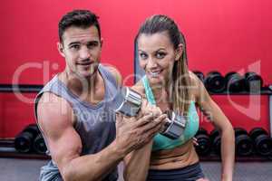 Portrait of two muscular people lifting a dumbbell