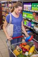 Pretty woman putting product in trolley