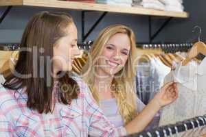 Smiling blonde woman showing clothes to her friend