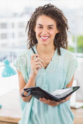 Smiling businesswoman holding a notebook and pen