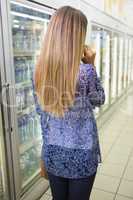 Pretty blonde woman buying frozen products and phoning