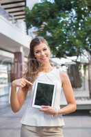 Portrait of smiling woman showing tablet computer and looking at